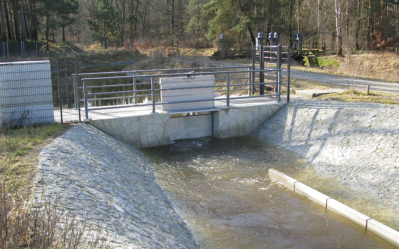 im Vordergrund das neue Überleiterbauwerk, Wasser steht davor an, im Hintergrund das Tranitzfließ
