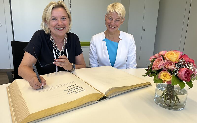 Zu sehen ist Bürgermeisterin Simone Taubenek, wie sie sich in das Goldene Buch der Stadt Wermelskirchen einträgt, rechts von ihr sitzt die Wermelskirchener Bürgermeisterin Marion Lück