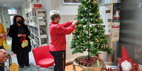 Bürgermeisterin Simone Taubenek beim Schmücken des Wunschbaumes mit kleinen runden Papierzetteln in Form von Weihnachtskugeln auf dem die Wünsche der Kinder stehen, in der Stadtbibliothek