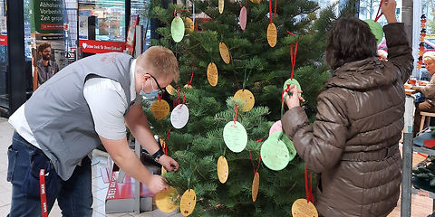Wunschbaum im REWE Markt wird mit Papierkugeln geschmückt, auf denen Wünsche geschrieben stehen