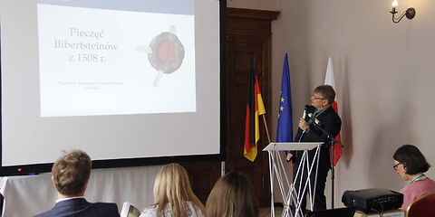 Zu sehen ist Herr Dr. Adam Górski während seiner Präsentation an einem Rednerpult