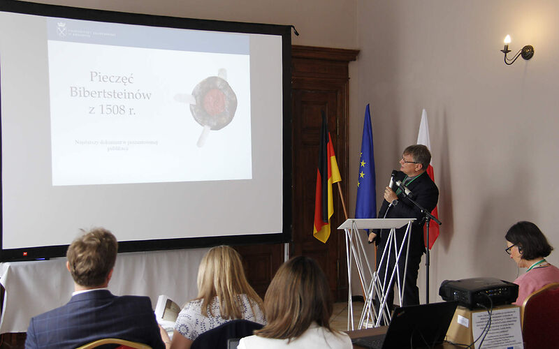 Zu sehen ist Herr Dr. Adam Górski während seiner Präsentation an einem Rednerpult