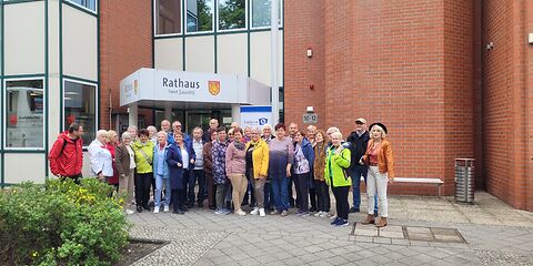 Die Gruppe Seniorinnen und Senioren steht aufgestellt vor dem Besuchereingang des Rathauses in der Lindenstraße.