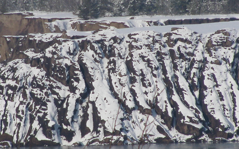 Der Schnee verziert die Rippen der Uferböschung.