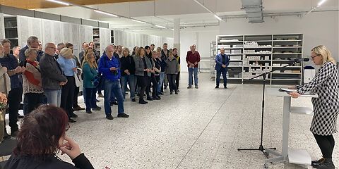 Bürgermeisterin Simone Taubenek steht am Rednerpult. Vor ihr steht eine Gruppe Besucher. Im Hintergrund sieht man die Schränke des Magazins des Stadtarchivs.