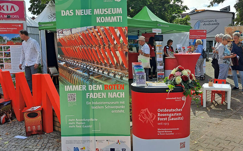 Zu sehen ist der Informationsstand der Stadt Forst (Lausitz) mit Aufstellern zur Stadt und zu touristischen Zielen wie dem Ostdeutschen Rosengarten, das zu Zeit neu entstehende Museum, bzw. mit Informationen über die Stadt