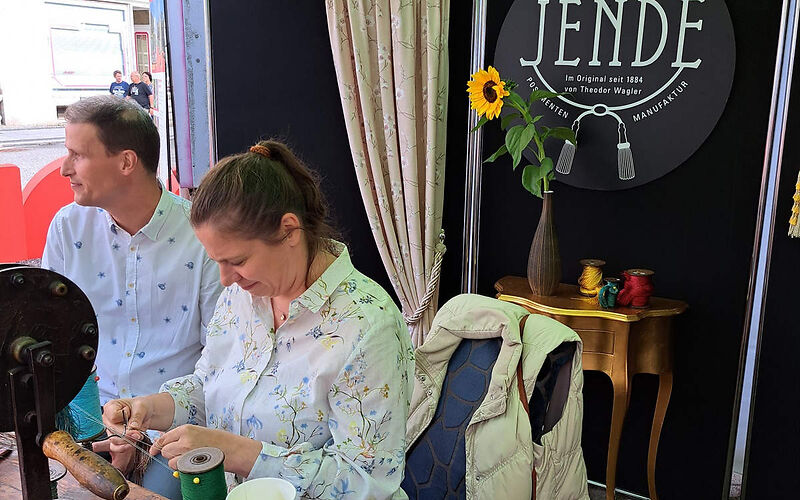 Die Jende Posamenten Manufaktur präsentiert sich, Frau Jende, Geschäftsführerin sitzt an einem Tisch mit Garnrollen und zeigt die Kunst der Herstellung von Posamenten