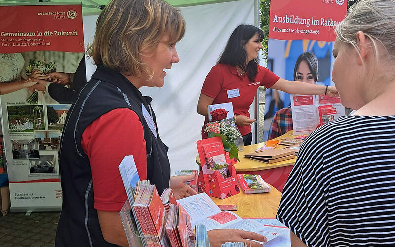 Zwei Mitarbeiterinnen der Stadt Forst (Lausitz) reichen Informationsmaterial über die Stadt Forst (Lausitz) an die Besucher des Brandenburgtages