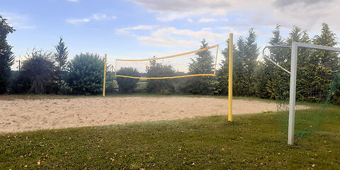 Das Beachvolleyballfeld umgeben von Bäumen im Hintergrund.