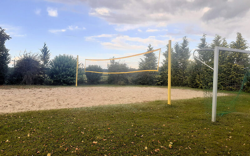 Das Beachvolleyballfeld umgeben von Bäumen im Hintergrund.