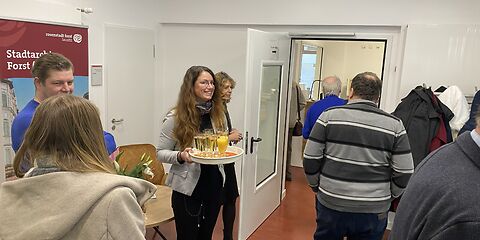 Im Eingangsbereich des Archivs wird Sekt oder Saft zum Anstoßen verteilt.