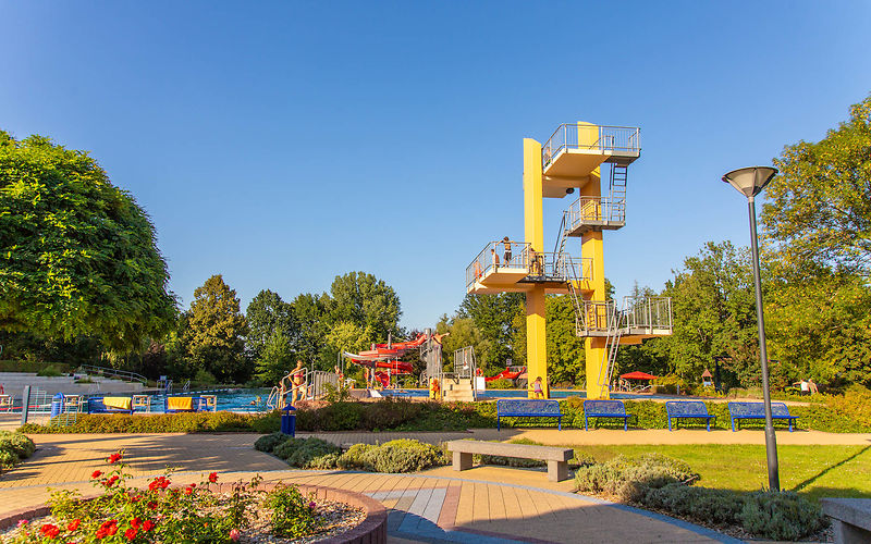 Blick auf den Sprungturm, das Schwimmer- und Nichtschwimmerbecken und die Rutschen