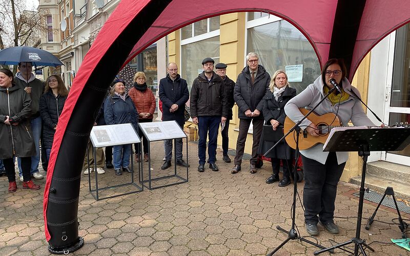 Eine Frau spielt Gitarre und singt dazu.