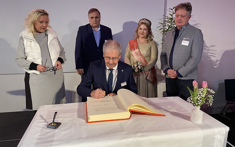 Harald Altekrüger trägt sich an einem Tisch in das Goldene Buch der Stadt Forst (Lausitz) ein. Hinter ihm stehen die Bürgermeisterin, der Vorsitzende der Stadtverordnetenversammlung und die Rosenkönigin.
