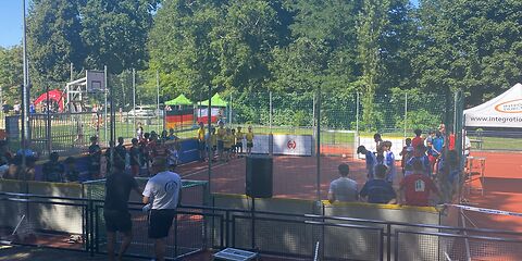 Auf dem eingezäunten Fußballfeld mit kleinen Toren, haben sich die Mannschaften an den Seitenrändern aufgestellt.