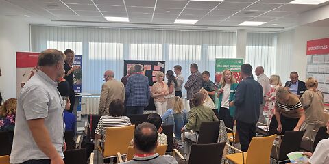 Menschen stehen vor einer Stellwand und verteilen Punkte auf den Karten 
