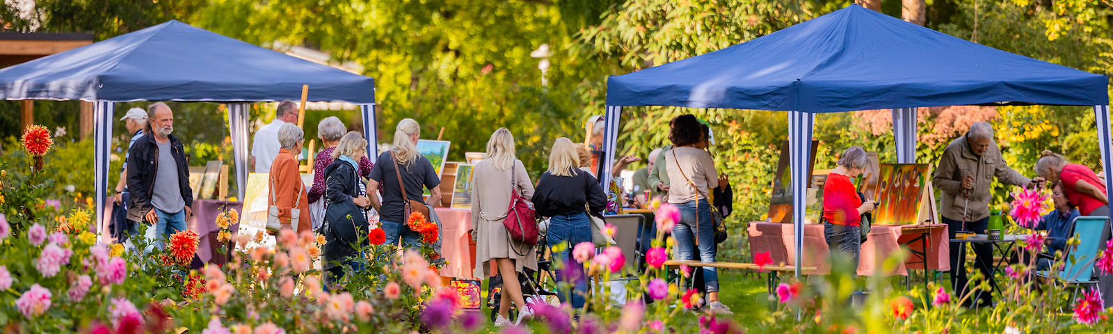 Personen stehen im Rosengarten vor 2 Pavillionen und schauen Gemälde an