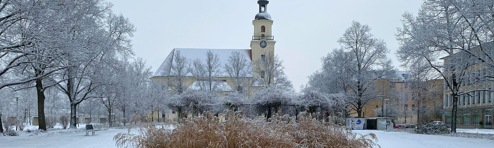 Der verschneite Park seitlich der Stadtkirche St. Nikolai mit Blick auf die Kirche.